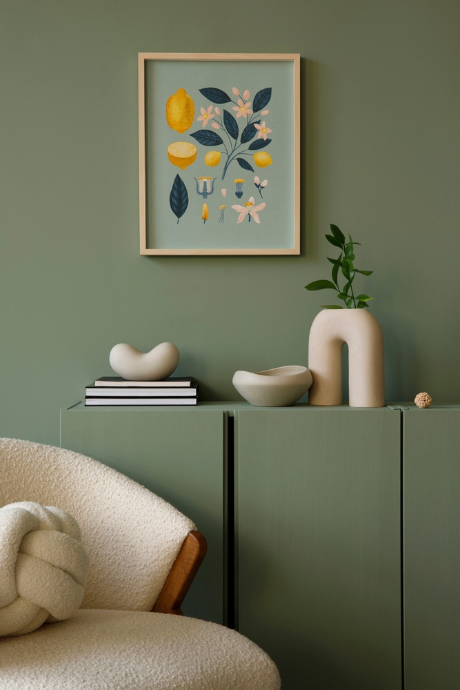 Cozy and elegant living room corner with a sage green color palette by Galaxy Interior Designers in Chennai, showcasing a framed botanical artwork, stylish minimalist decor, and a plush cream chair, perfect for modern interior design inspiration